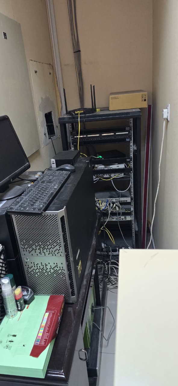 Office server room with a tower server and network rack before decommissioning